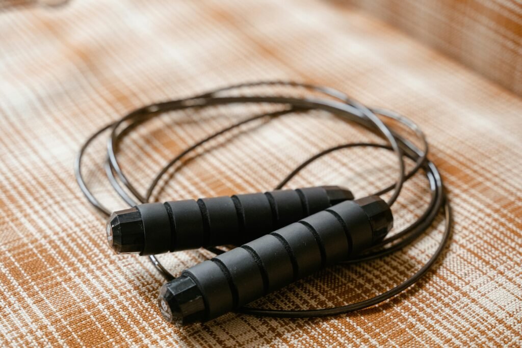 pexels photo 8032841 8032841 A black jump rope coiled on a patterned plaid surface, highlighting fitness equipment.